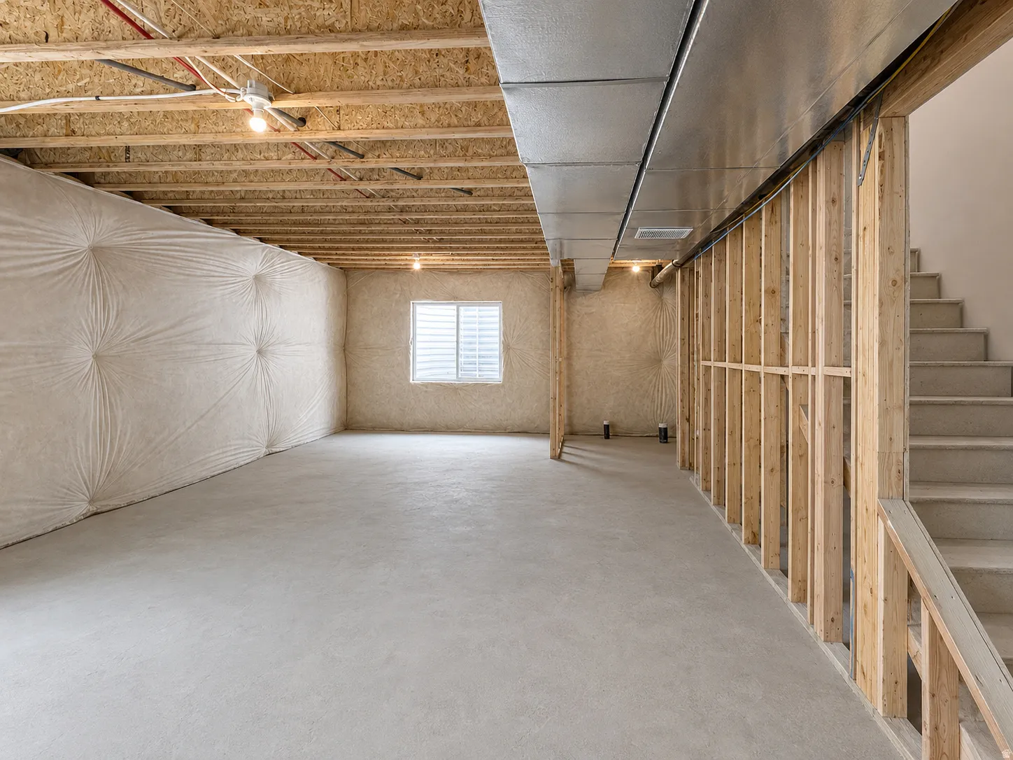 Unfinished basement featuring a concrete floor, framed walls, and an exposed ceiling with ductwork