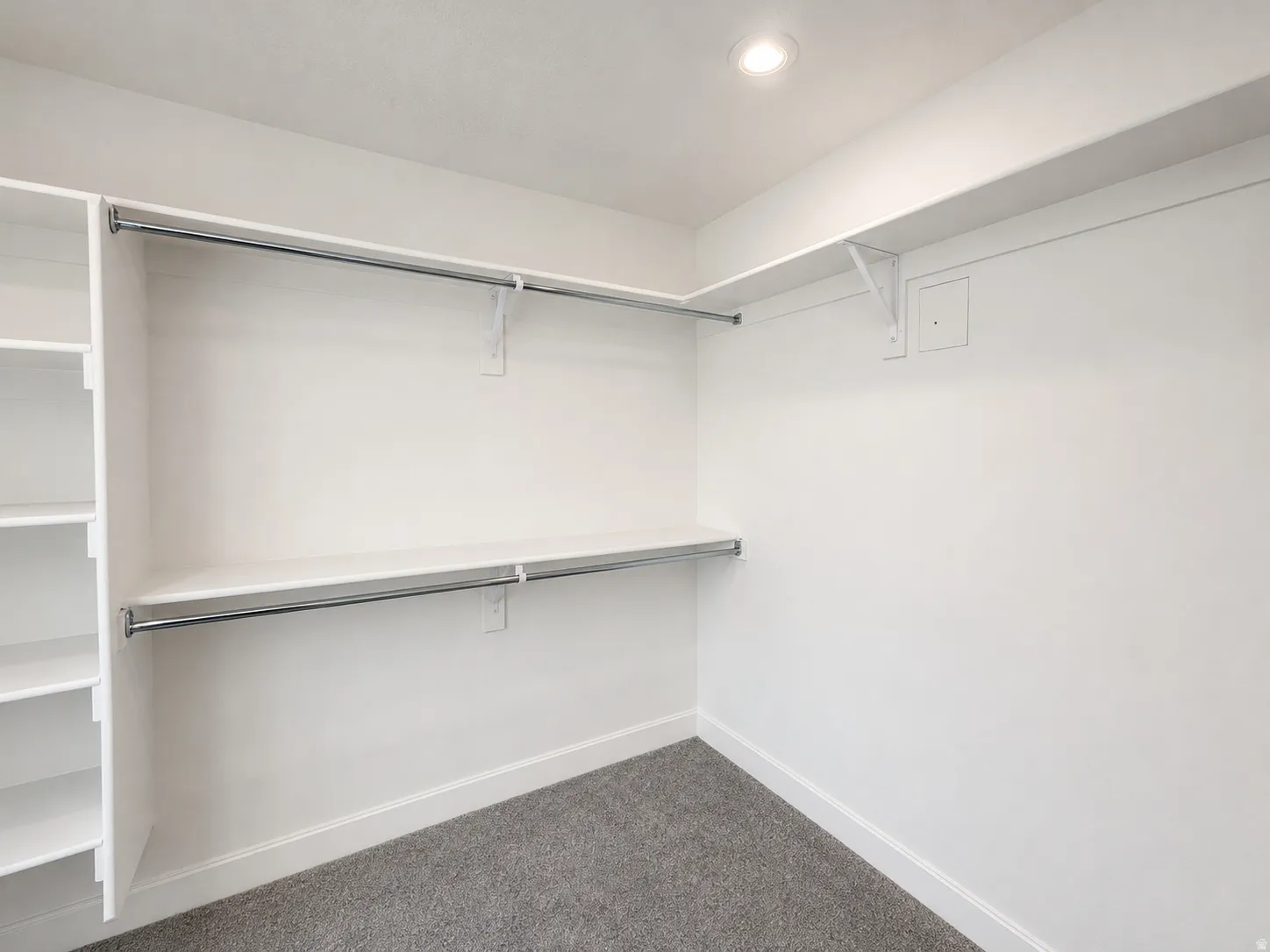 Walk-in closet featuring white walls, gray carpet flooring, recessed lighting, built-in shelving, and chrome hanging rods