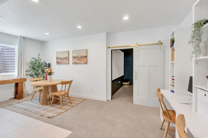 Open concept space featuring recessed lighting, light-toned carpeting, and a white paneled barn door with brass hardware