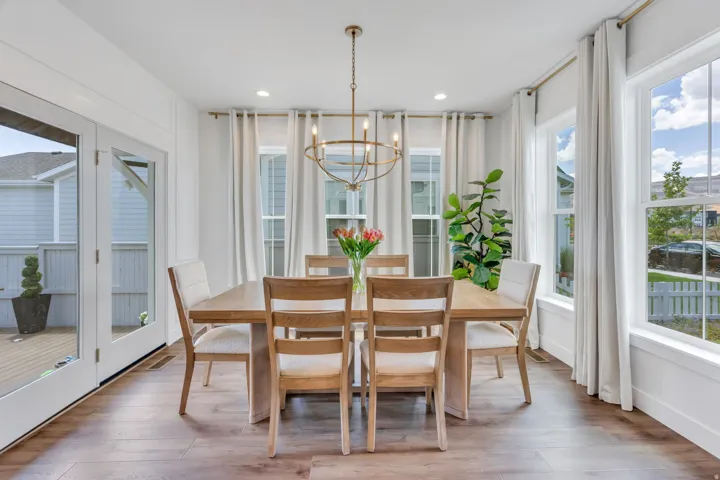 Dining area featuring wood-finish flooring, a brass chandelier, and white trim