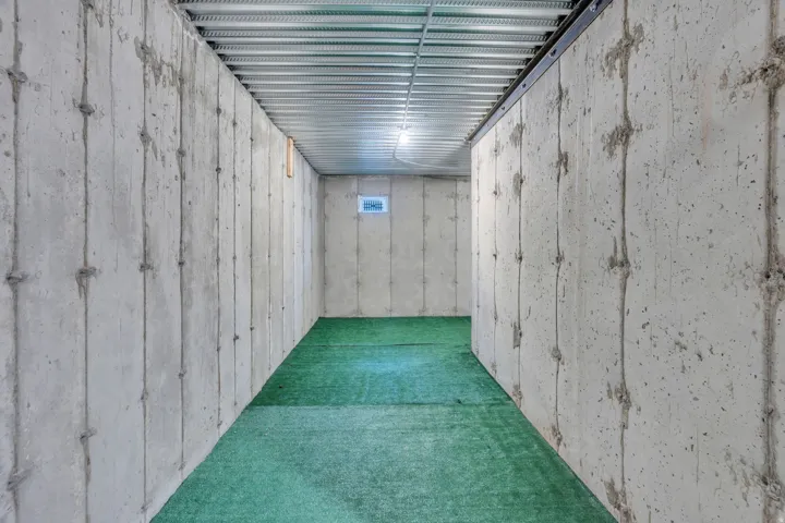 Concrete foundation walls featuring a small fixed window and an exposed ceiling with metal joists