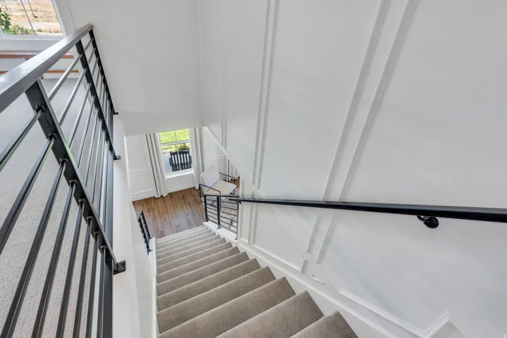 Carpeted staircase with dark metal railings and a wood-finish floor landing