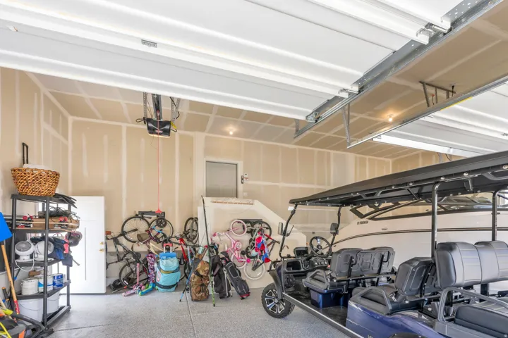 Spacious garage featuring a durable epoxy floor, finished walls, and a convenient side entry door