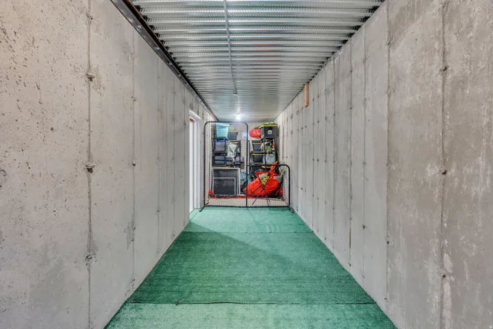 Finished concrete walls define this hallway, featuring a durable green turf-style floor covering