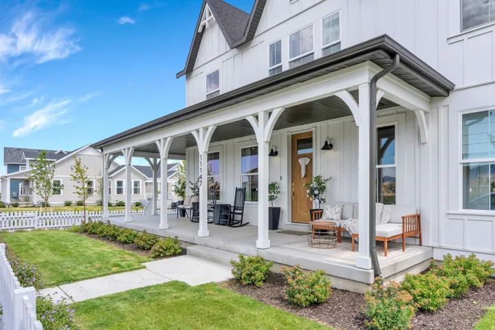 White board-and-batten exterior featuring a full-length front porch with decorative arched supports, dark window trim, and a prominent dark roofline