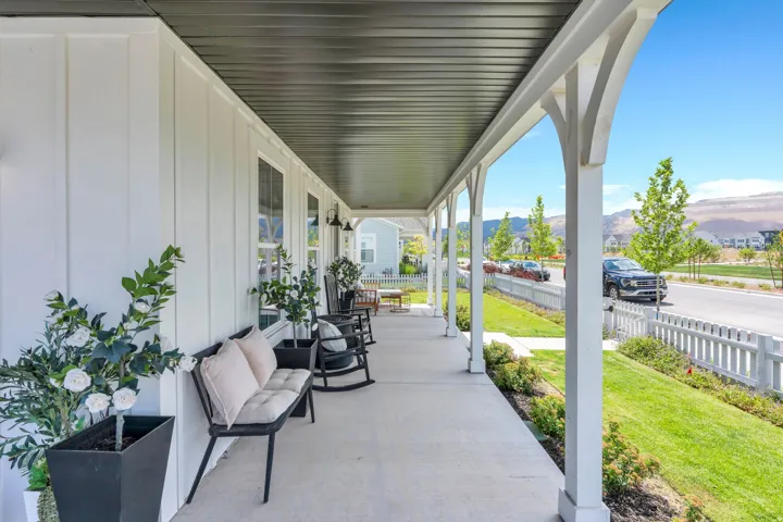 Inviting covered porch featuring white board and batten siding, multiple windows, and a dark soffit