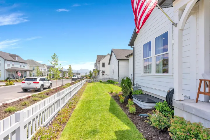 White picket fence bordering a manicured lawn and landscaping