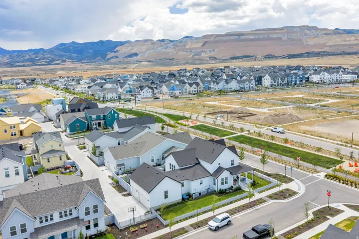 Expansive aerial view of a residential community featuring diverse architectural styles, newly constructed homes, and mountain scenery