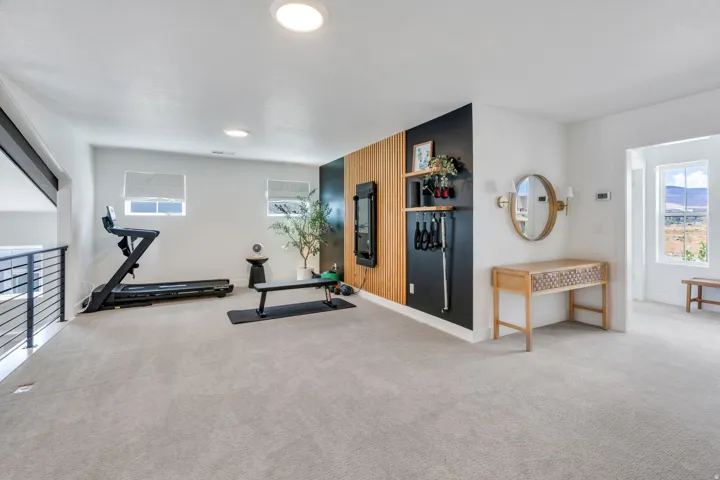 Spacious carpeted room featuring a modern accent wall with vertical wood paneling and black painted sections
