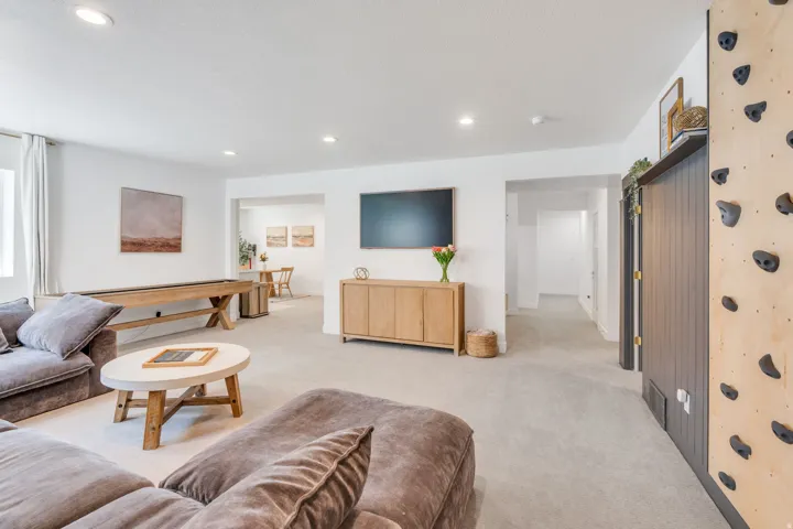 Open-concept recreation area featuring light-toned carpeting, recessed lighting, and a shuffleboard table