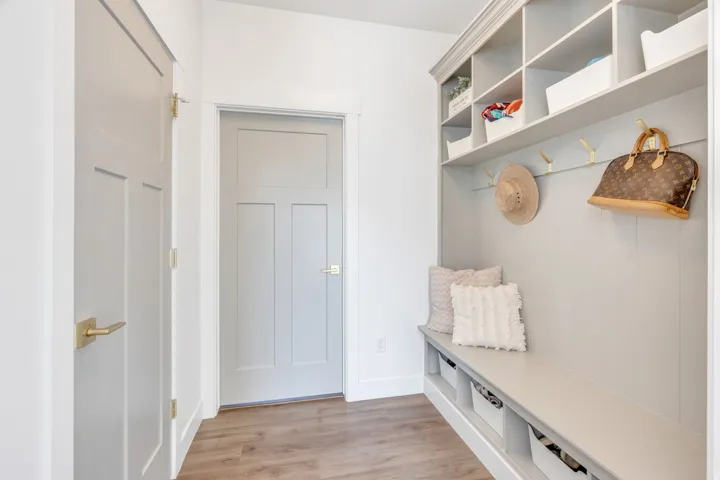 Built-in entryway organization system featuring a bench, upper shelving, and wall hooks