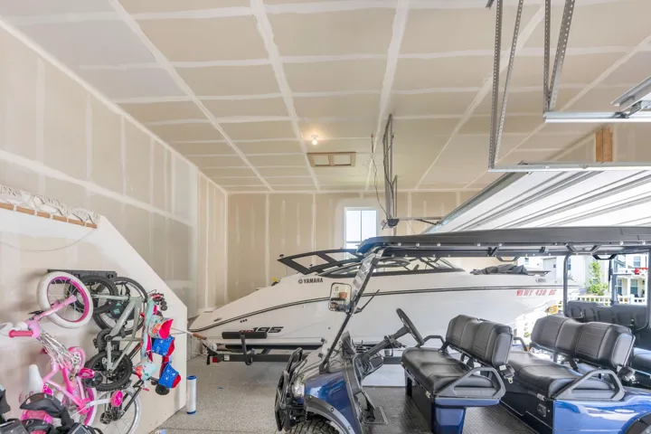 Spacious garage with an epoxy-coated floor, painted drywall, and a large overhead door