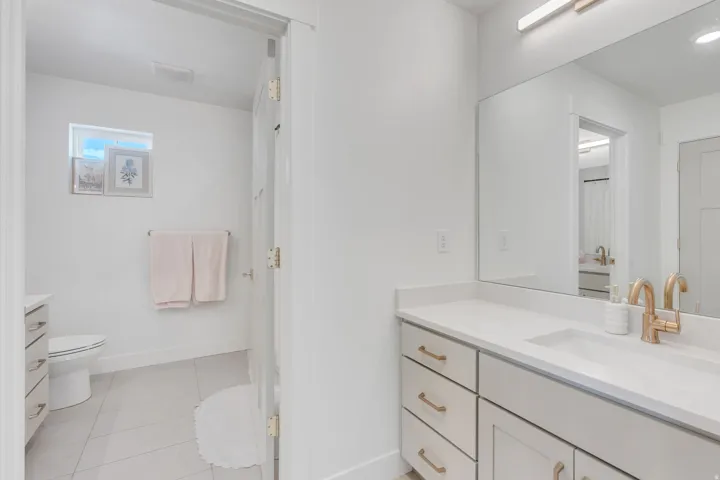 Bathroom featuring a vanity with a white countertop, undermount sink, and brass-finish faucet