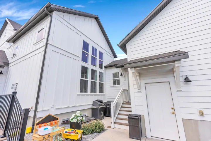 Multi-story exterior featuring white board and batten siding, horizontal siding, multiple large windows, a covered entryway, and exterior lighting fixtures