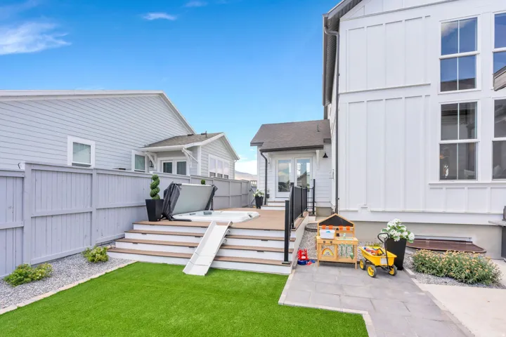 Expansive backyard featuring a multi-level deck, a built-in hot tub, and a synthetic turf lawn