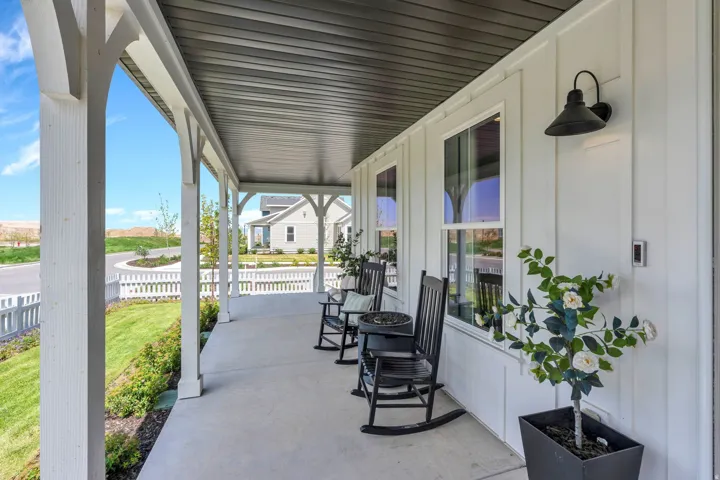 Expansive covered porch featuring a concrete surface, white columns, and a dark paneled ceiling
