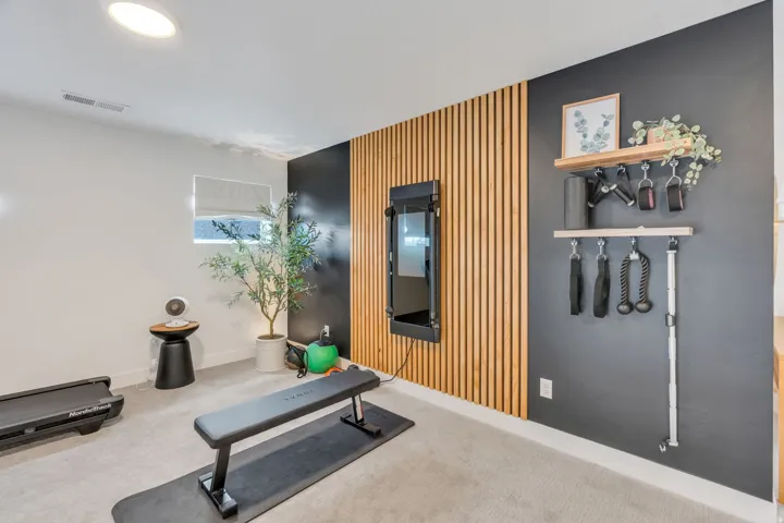 Dedicated fitness area featuring a wood slat accent wall, recessed lighting, and light-toned carpeting