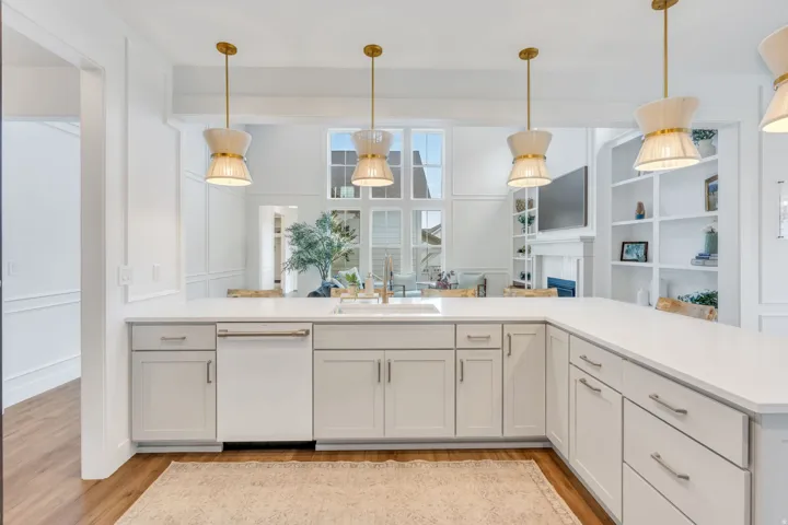 Bright kitchen featuring a wrap-around countertop, light-toned cabinetry, built-in sink, and stainless steel dishwasher