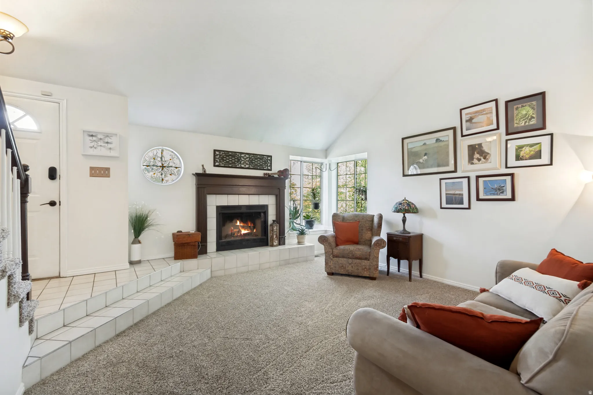 Vaulted living space featuring a wood-burning fireplace with a dark wood mantel and a tile hearth