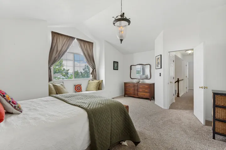 Vaulted ceiling bedroom featuring a built-in window seat, large window, and wall-to-wall carpeting