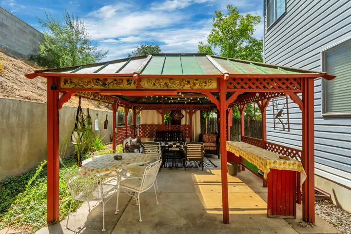 Outdoor patio featuring a red wooden gazebo with an ornate decorative fascia and a green metal roof
