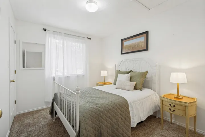 Bedroom featuring wall-to-wall carpeting, a large window with sheer curtains, a flush-mount ceiling light, and white painted walls