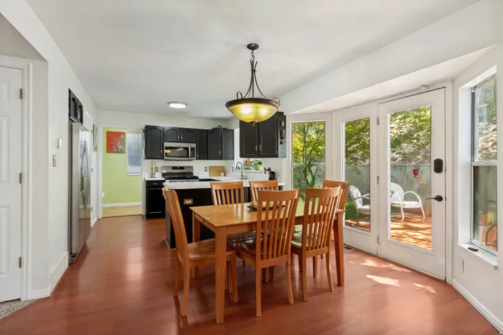 Kitchen with dark cabinetry and stainless steel appliances, featuring wood-finish flooring