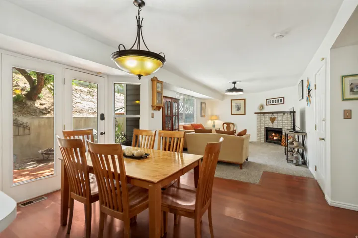Open-concept dining area with wood-finish flooring, featuring a classic chandelier and French doors providing outdoor access