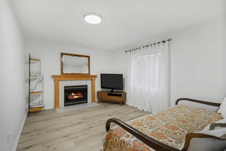 Light wood-finish flooring throughout, featuring a fireplace with a light wood mantel and tiled surround