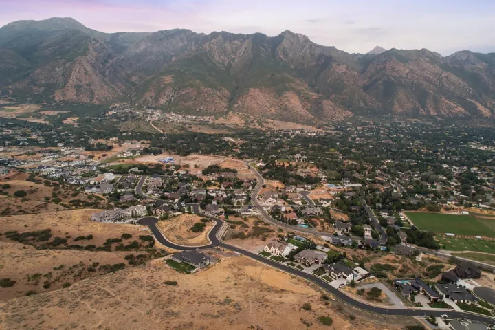 Expansive mountain landscape frames a developing residential area with paved streets and established homes