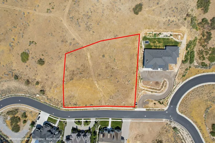 Expansive undeveloped land parcel featuring a gentle slope, existing access roads, and proximity to established residential properties