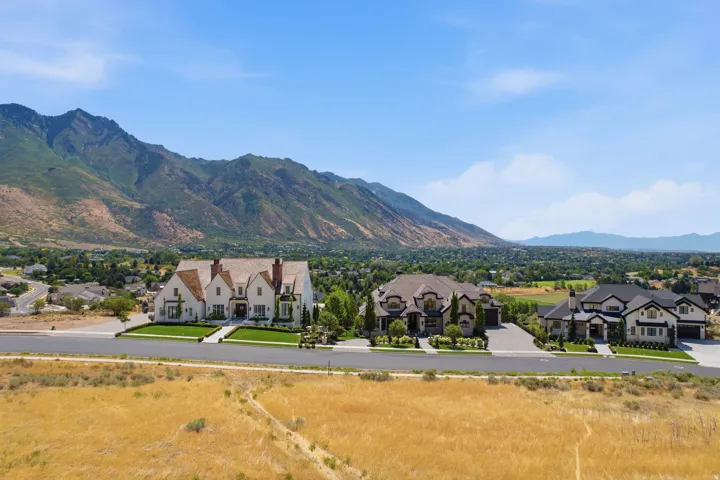 Expansive property featuring a grand residence with multiple gables, brick chimneys, and a light-colored exterior
