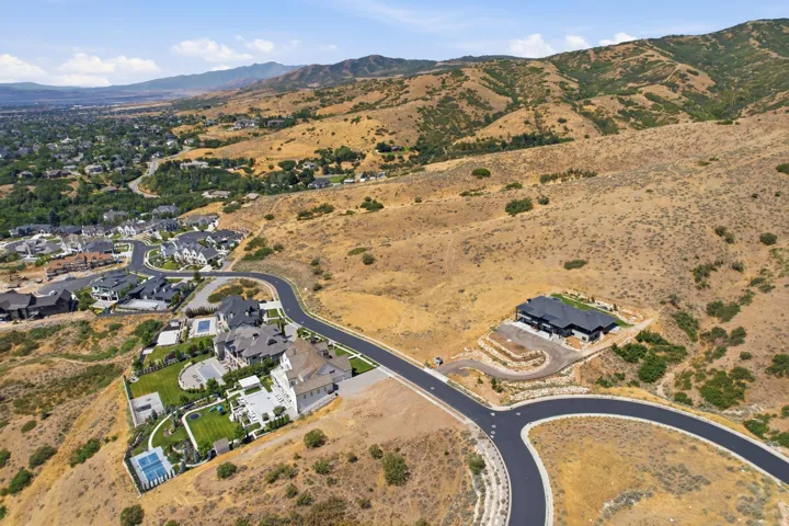 Expansive residential development with paved roadways, individual properties featuring distinct landscaping, and mountainous terrain