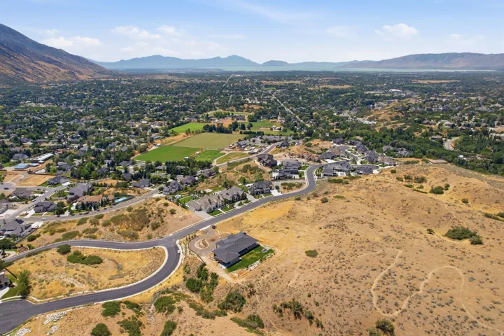 Aerial perspective showcasing a residential development with mountain backdrops and distant body of water