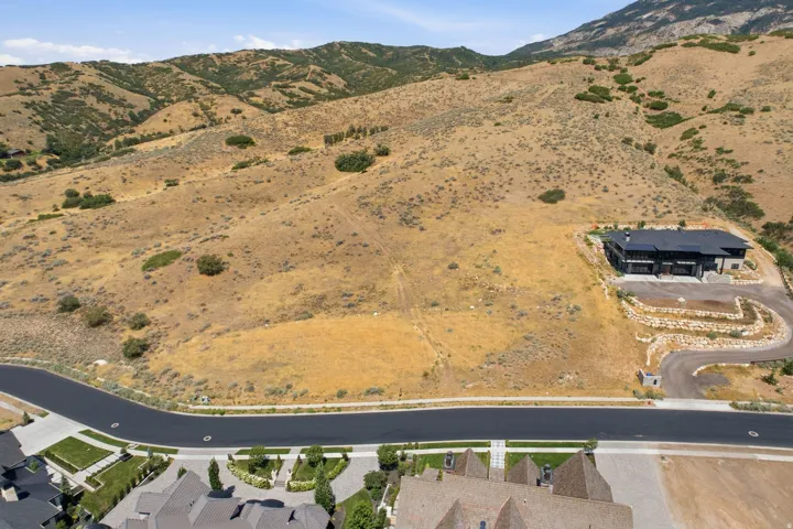 Expansive undeveloped land parcel with a paved road frontage, surrounded by rolling hills and distant mountains