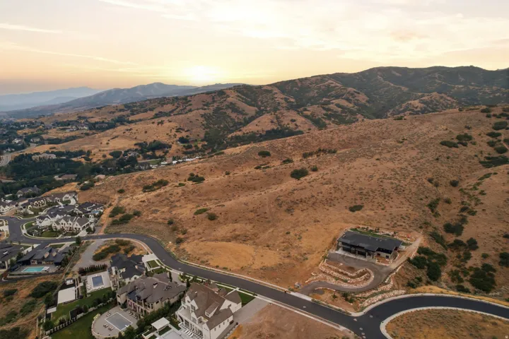Expansive mountain landscape with a newly constructed residence featuring a dark facade and terraced landscaping