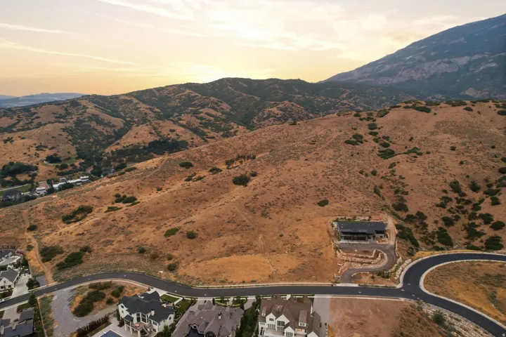 Sloping mountain terrain with sparse vegetation, featuring a modern dwelling on a terraced lot