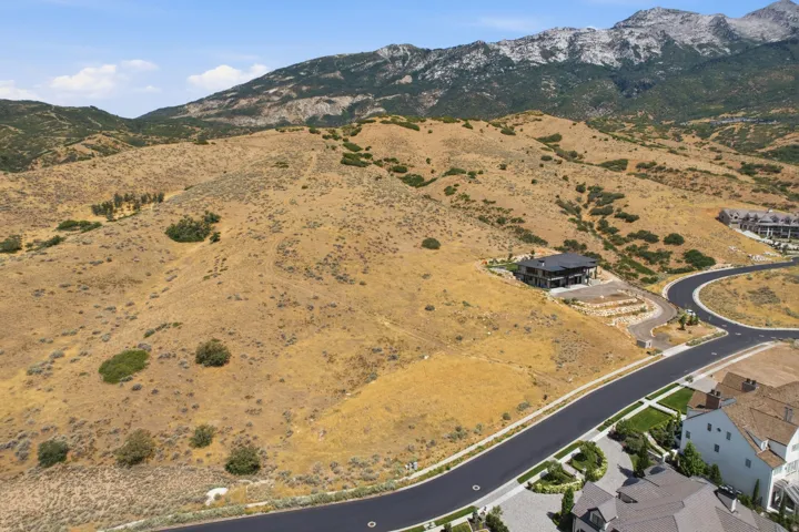 Expansive hillside property featuring a modern residence, paved roadways, and a mountainous backdrop