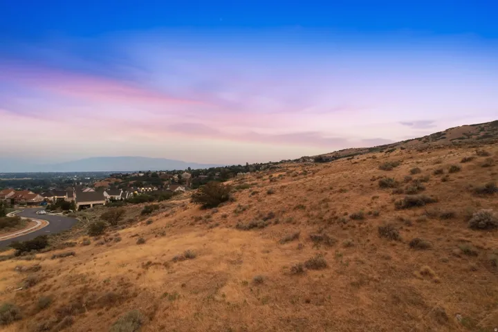 Hillside property featuring natural arid landscaping with sparse shrubs and grasses