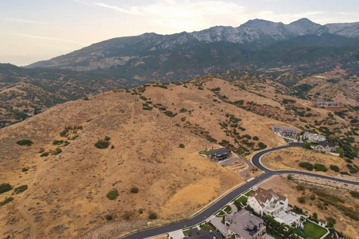 Expansive mountainous terrain featuring scattered residential properties, paved roadways, and natural vegetation