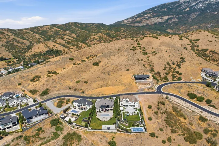 Aerial perspective showcasing a residential development nestled into mountainous terrain with established homes and undeveloped parcels