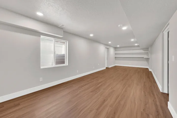 Spacious room featuring wood-finish flooring, recessed lighting, and light gray walls with white baseboards