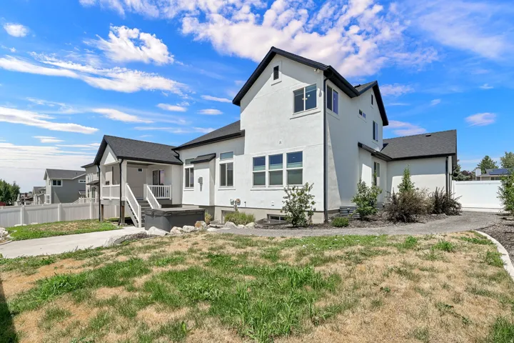 Contemporary white stucco exterior with dark trim accents, featuring multiple windows and a covered porch with white railings