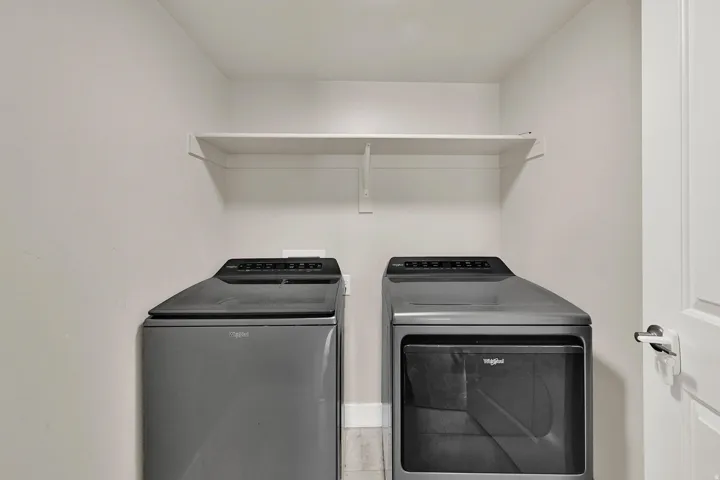 Laundry area featuring a top-load washing machine, front-load dryer, and an upper storage shelf