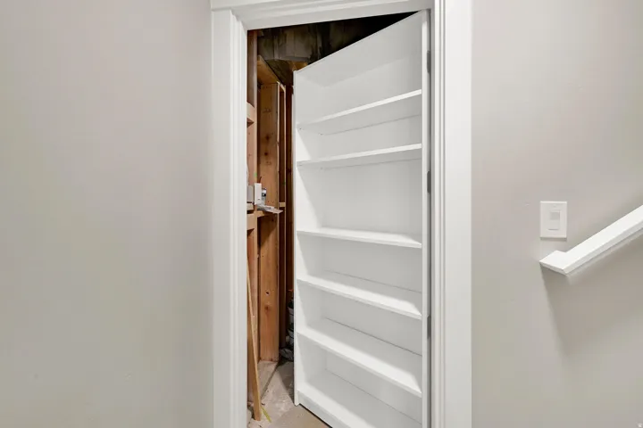 Hidden storage compartment with built-in shelving, concealed behind a functional door