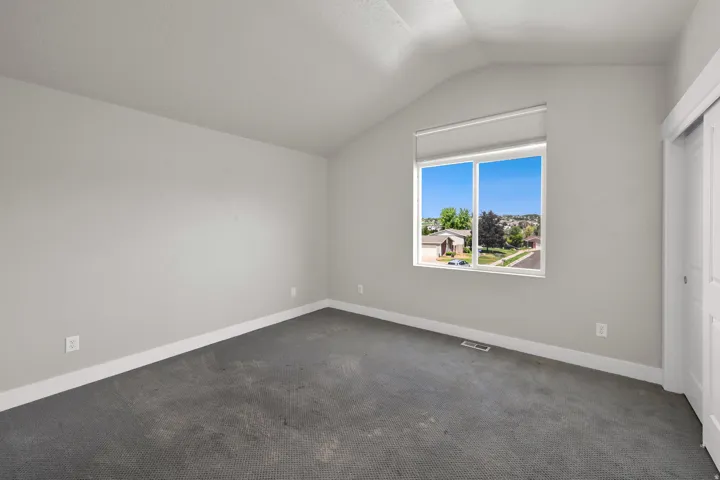 Bright room featuring a vaulted ceiling and a large window with roller shade