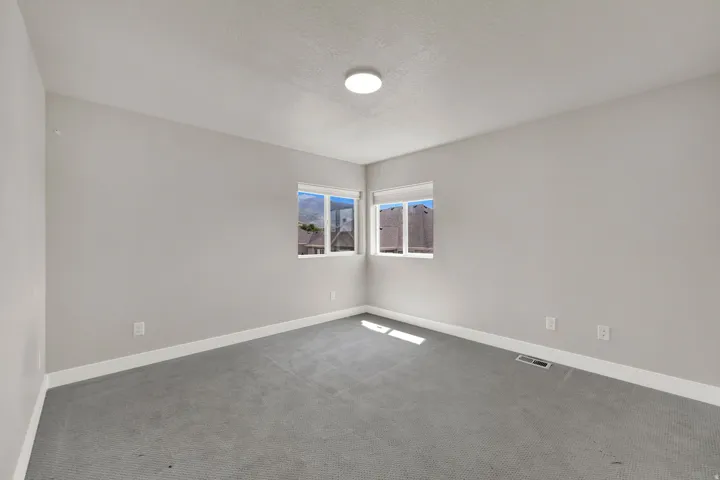 Bright room featuring light grey walls and grey carpet flooring