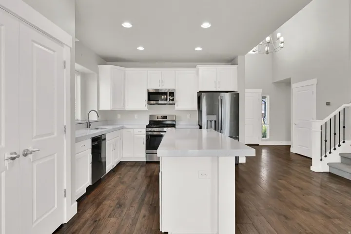 Kitchen featuring an island with stone countertops, white cabinetry, and stainless steel appliances