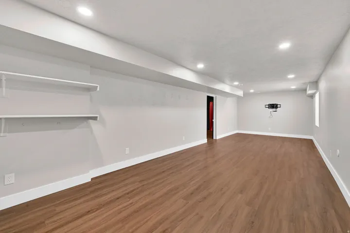 Spacious room featuring wood-finish flooring, recessed lighting, and crisp white baseboards