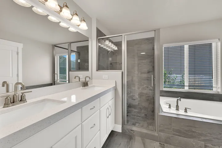 Primary bathroom featuring a dual vanity with undermount sinks, a quartz countertop, and white cabinetry